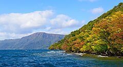 Il Lago Towada con alberi colorati in autunno sullo sfondo.