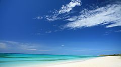Spiaggia di sabbia bianca sull'isola di Lifou con cielo blu e mare calmo.