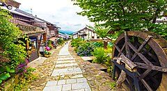Strada tradizionale a Magome con case di legno e un antico mulino ad acqua.