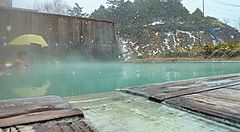 Onsen Manza innevato con vapore e paesaggio invernale.