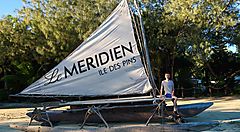 Barca a vela con logo Le Méridien su una spiaggia dell'Isola dei Pini.
