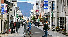 Strada commerciale a Nakamachi, con persone che camminano e vanno in bici.
