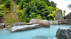 Onsen all'aperto nelle montagne di Okuniku circondato da rocce e alberi.