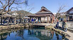 Lago di Oshino Hakkai con persone che ammirano l'acqua e le costruzioni tradizionali circostanti.