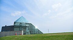 Struttura moderna in vetro nel Parco Moerenuma con cielo azzurro sullo sfondo.