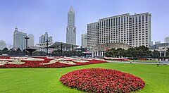Piazza del Popolo a Shanghai con giardino fiorito e grattacieli sullo sfondo.