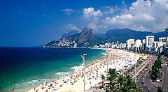 Spiaggia affollata a Rio de Janeiro, Brasile, con montagne sullo sfondo.