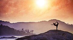 Persona pratica yoga su una roccia al tramonto in India.