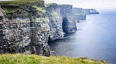 Scogliere d'Irlanda a picco sul mare con cielo leggermente nuvoloso.