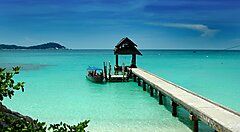 Ponton in legno che si estende su un mare cristallino in Malesia.