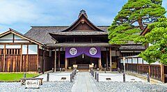 Takayama Jinya, edificio storico in legno con giardino pietroso e albero verde.