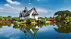 Tempio thailandese storico riflesso in un lago con cielo azzurro.