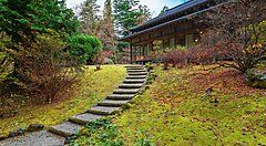 Scalinata tra giardino muschioso e Villa Tamozawa in autunno.