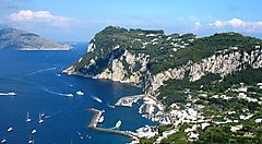 Costa e paesaggio dell'isola di Capri con barche e mare azzurro.
