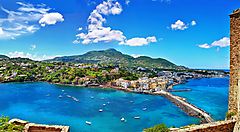 Veduta panoramica di Ischia con il mare blu e il paesaggio collinare.
