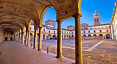 Piazza medievale di Mantova con loggia e torre sullo sfondo.
