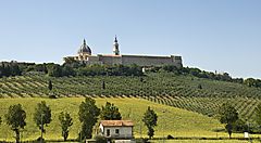 Paesaggio delle colline delle Marche con edificio storico sullo sfondo.