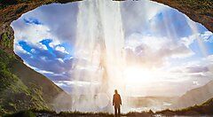 Una persona ammira una cascata in Islanda con il cielo nuvoloso.