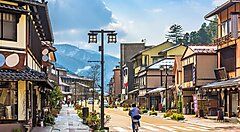 Strada tradizionale a Yamanaka Onsen con case in legno e montagne sullo sfondo.