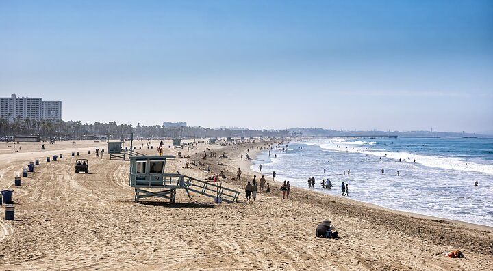 Spiaggia affollata in California con torrette di salvataggio e bagnanti.