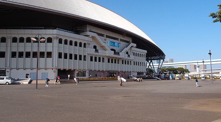 L'Ariake Coliseum a Tokyo con persone che camminano all'esterno.