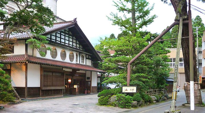 Ingresso di un tradizionale ryokan ad Awazu Onsen, circondato da alberi.