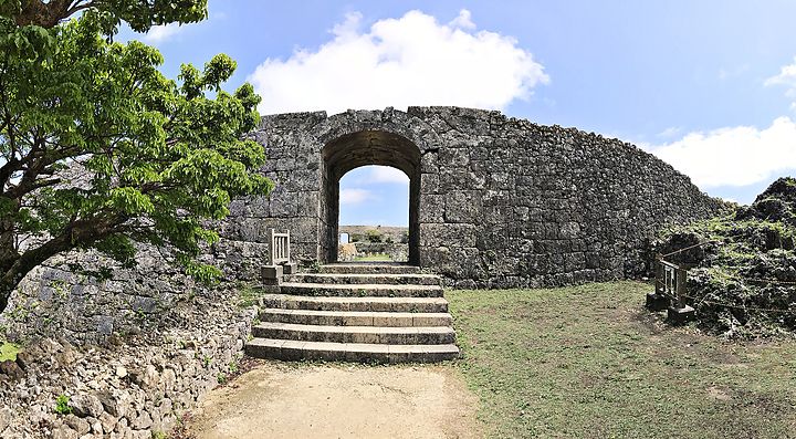 Rovine del Castello di Nakagusuku con arco di pietra e vegetazione.