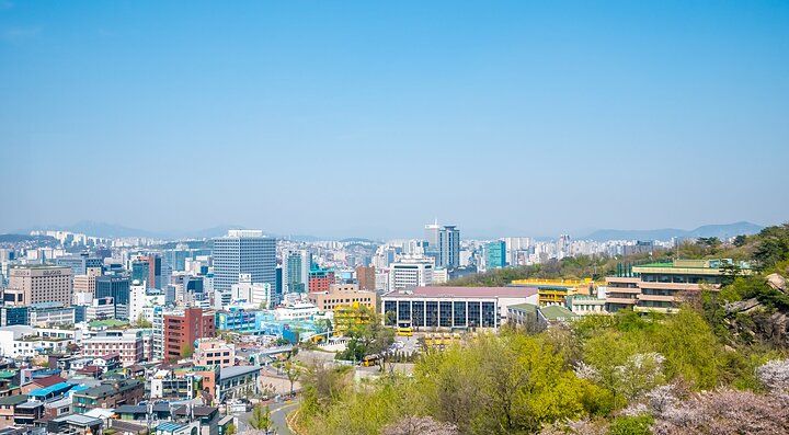 Vista panoramica della città di Seoul con edifici moderni e colline verdi.