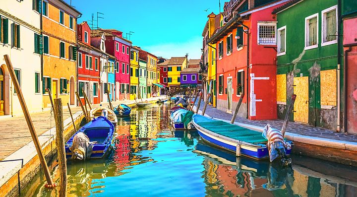 Case colorate lungo il canale di Burano con barche ormeggiate.