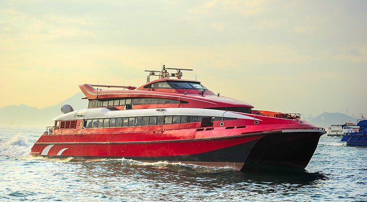 Traghetto rosso naviga verso Macao al tramonto.