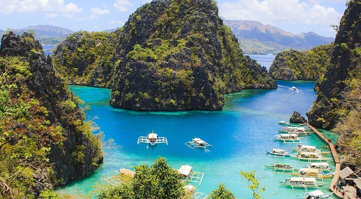 Laguna turchese di Boracay con barche tradizionali e colline verdi.