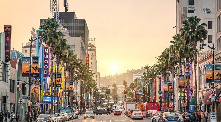 Un viale trafficato a Los Angeles con palme e insegne luminose.