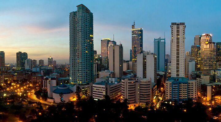 Skyline di Manila al tramonto con grattacieli illuminati.