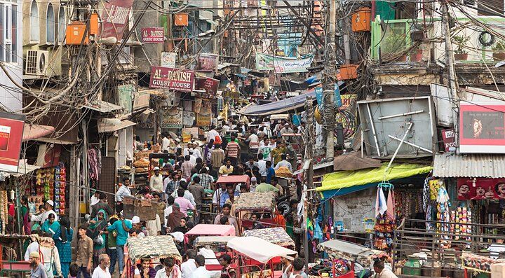 Strada affollata e vivace a Nuova Delhi con bancarelle e persone.