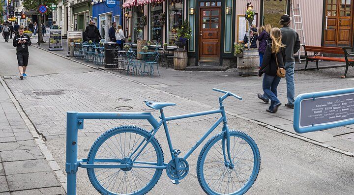 Bicicletta blu parcheggiata in una via di Reykjavik, con persone a passeggio.