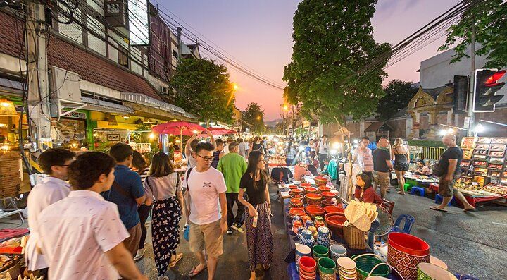 Mercato notturno affollato in Thailandia con bancarelle e visitatori.