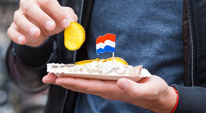 Snack olandese con bandierina e cetriolo in mano.