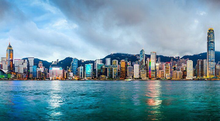 Lo skyline di Hong Kong visto dall'acqua sotto un cielo nuvoloso.