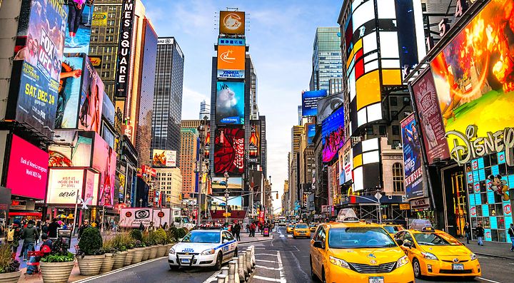 Strada trafficata a Times Square, New York, con taxi gialli e cartelloni luminosi.
