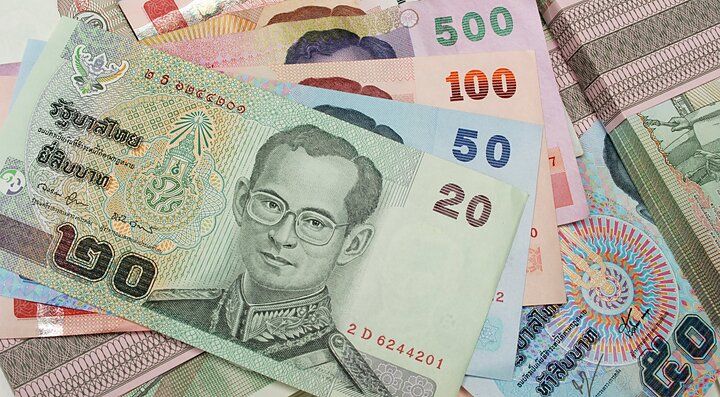 Banconote thailandesi di diversi tagli sparse sul tavolo.