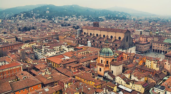Veduta aerea del centro storico di Bologna con edifici e colline.