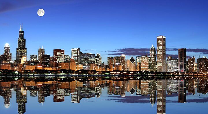 Skyline notturno di Chicago riflesso nel lago con la luna piena.