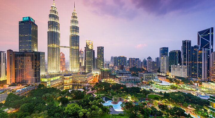 Skyline serale di Kuala Lumpur con le Petronas Towers illuminate.