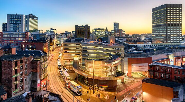 Panorama urbano di Manchester al tramonto con edifici e strade.