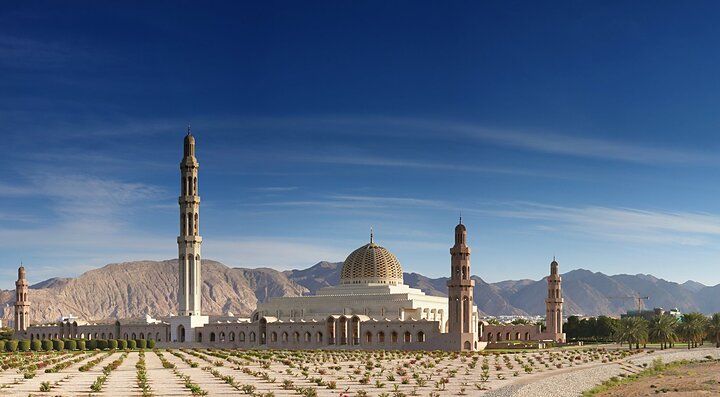 La Grande Moschea del Sultano Qaboos a Muscat con montagne sullo sfondo.