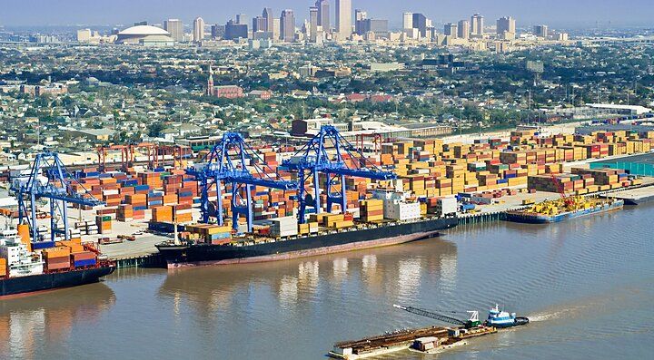 Porto affollato a New Orleans con container e skyline della città sullo sfondo.