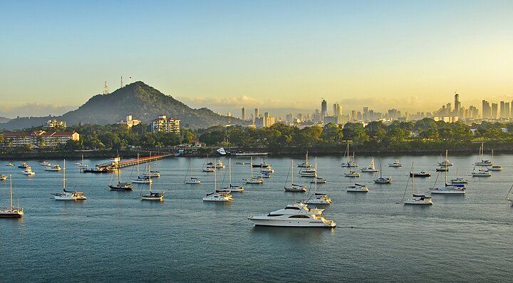 Barche a vela ormeggiate nella baia con skyline di Panama sullo sfondo.