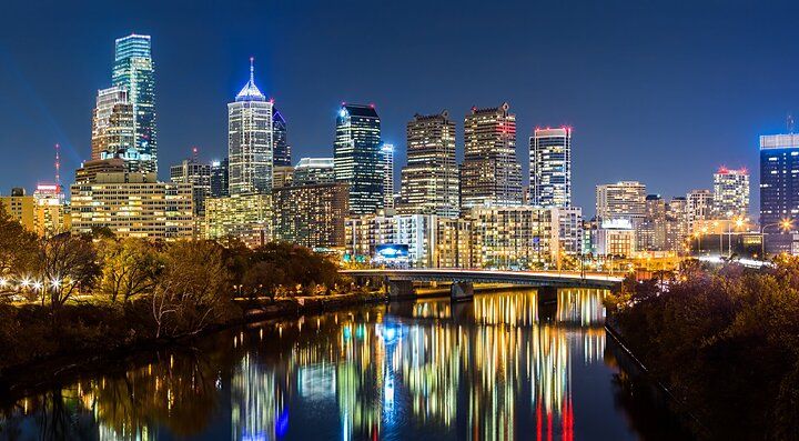 Skyline di Philadelphia illuminata di notte riflessa nel fiume.