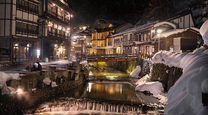 Strada illuminata di Ginzan Onsen con edifici tradizionali e neve.