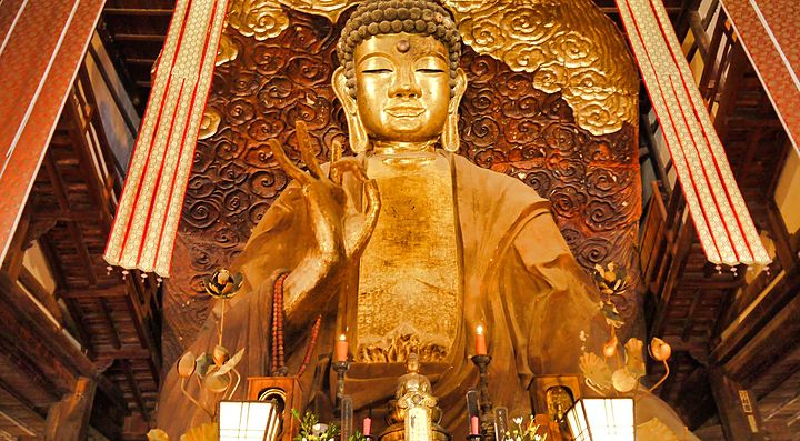 La statua del Grande Buddha di Gifu, ornata e dorata, all'interno di un tempio.